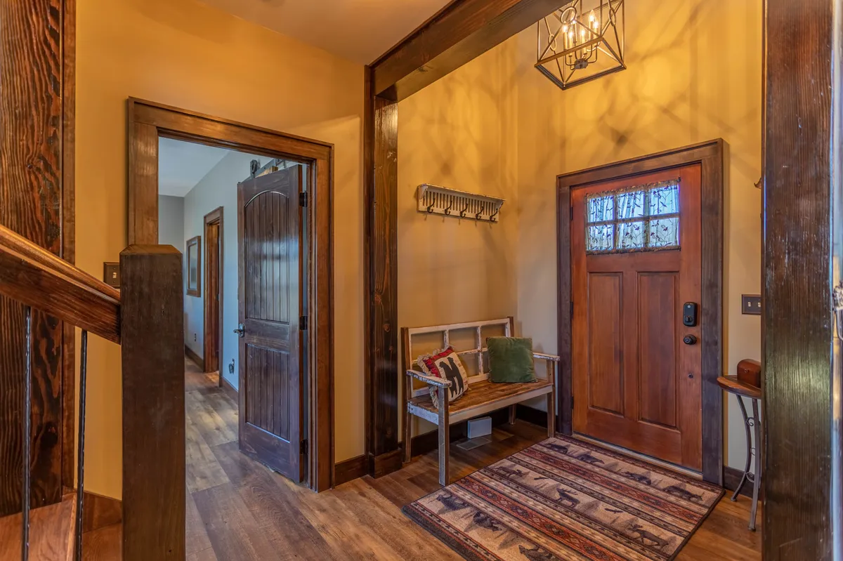 The lodge’s inviting entryway features a front door, an entryway bench, and a welcoming rug. This transitional space bridges the comfort of the interior with access to the outdoors, highlighting the convenience for guests coming or going with their pets.