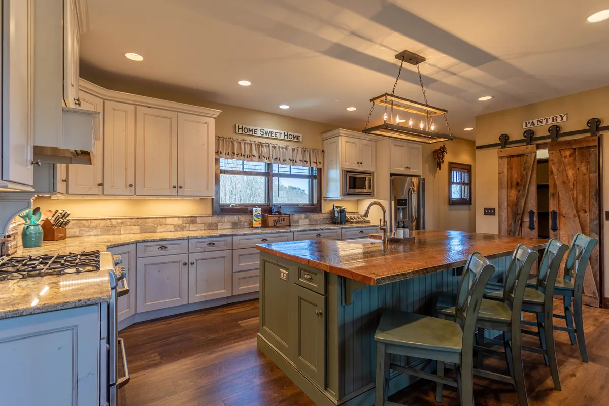 A welcoming kitchen space with a central island, visible pantry door, and a window offering natural light. The island is ideal for meal prep or enjoying a casual breakfast, while the open design connects seamlessly to the rest of the home.