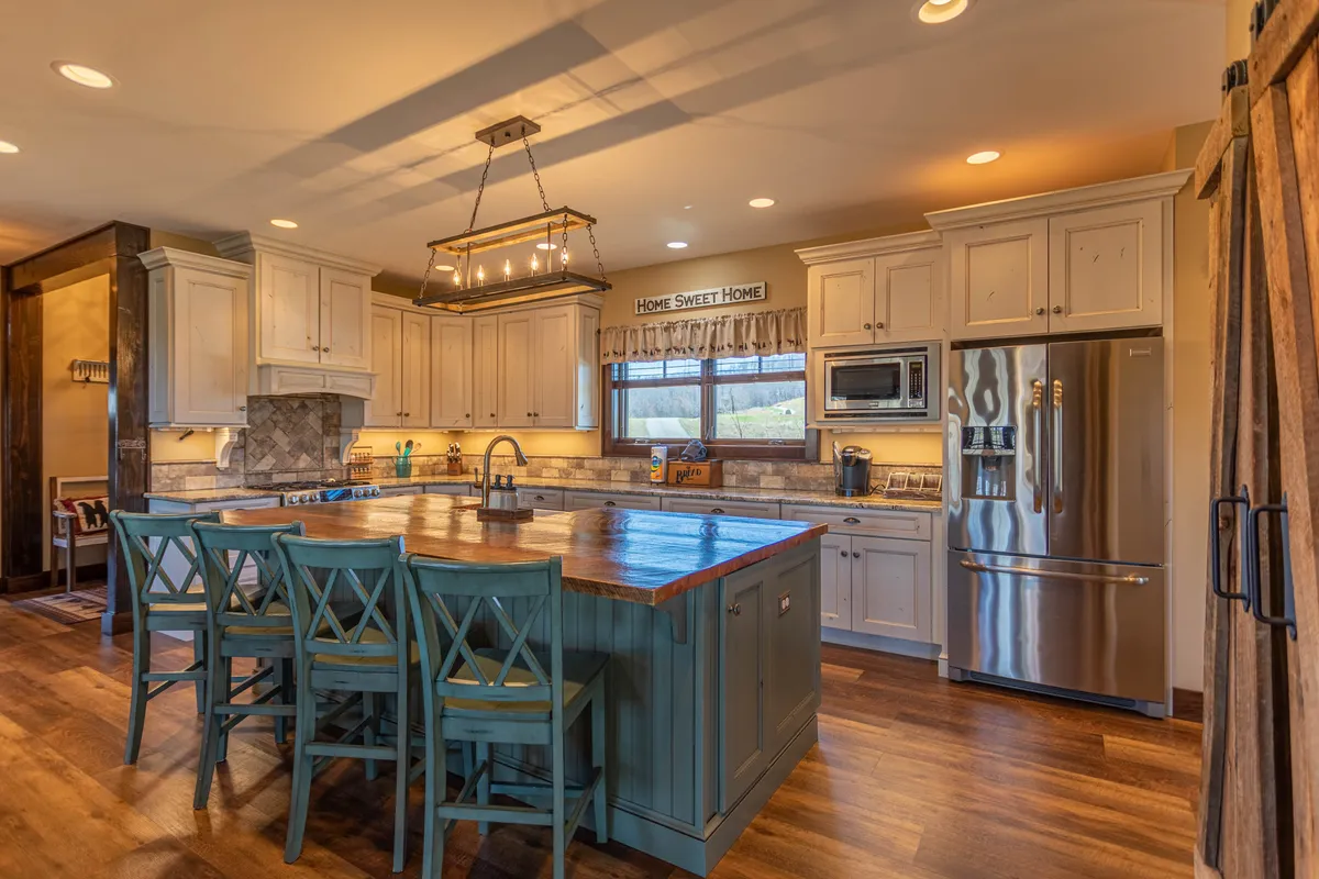 This image showcases a cozy, inviting kitchen space centered around a wooden island, under a stylish light fixture. The cabinets feature glass doors that add a touch of elegance, and the overall atmosphere suggests an ideal space for cooking, entertaining, or preparing local finds from the vineyard.
